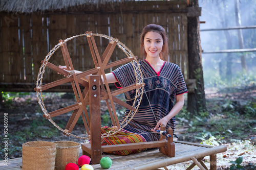 Beautiful Thai women smile in karen suit spinning thread on a bamboo mat in a forest nature local village Thailand photo