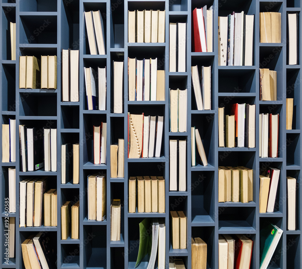 Books on blue wooden bookshelf. Book fore edges facing the front. Books on blue wooden bookshelf. Book fore edges facing the front.