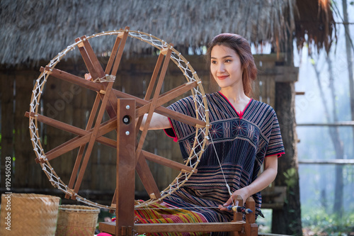 Quadro em tela Beautiful Thai women smile in karen suit spinning thread on a bamboo mat in a fo