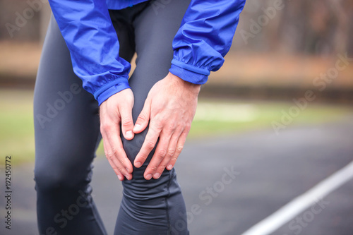 Cropped shot of a young runner holding his injured knee while running.