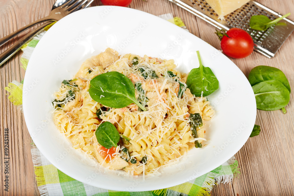 Pasta fusilli with chicken meat, spinach, tomatoes, cream sauce and cheese