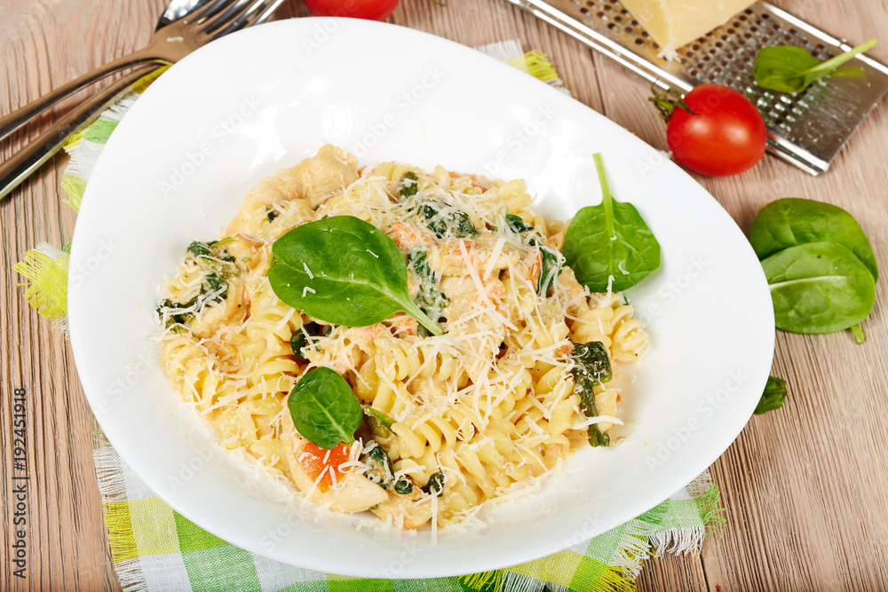 Pasta fusilli with chicken meat, spinach, tomatoes, cream sauce and cheese Pasta fusilli with chicken meat, spinach, tomatoes, cream sauce and cheese