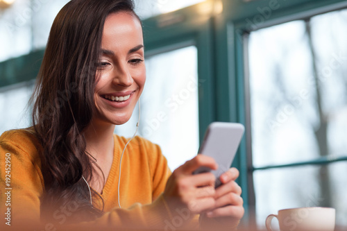 Whats new. Merry cheerful irresistible woman grinning while typing on smartphones and drinking tea Free Download Whats new. Merry cheerful irresistible woman grinning while typing on smartphones and drinking tea - GFXLoad