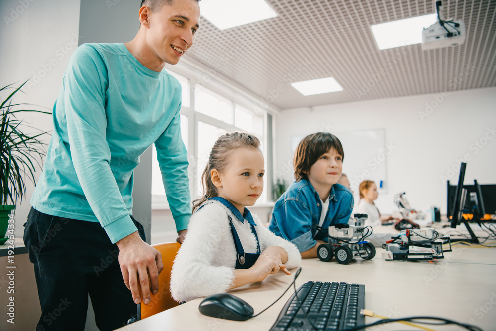 Obraz premium young teacher helping his teen students with diy robot on stem education class