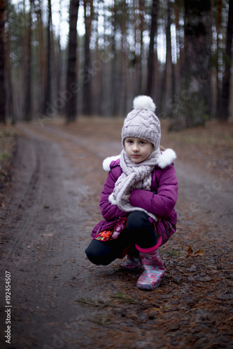 Little cute girl posing on the road in the pine forest in autumn time
