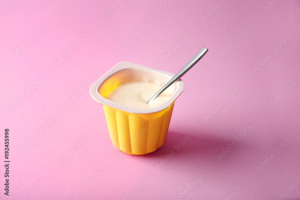 Plastic cup with yummy yogurt on color background
