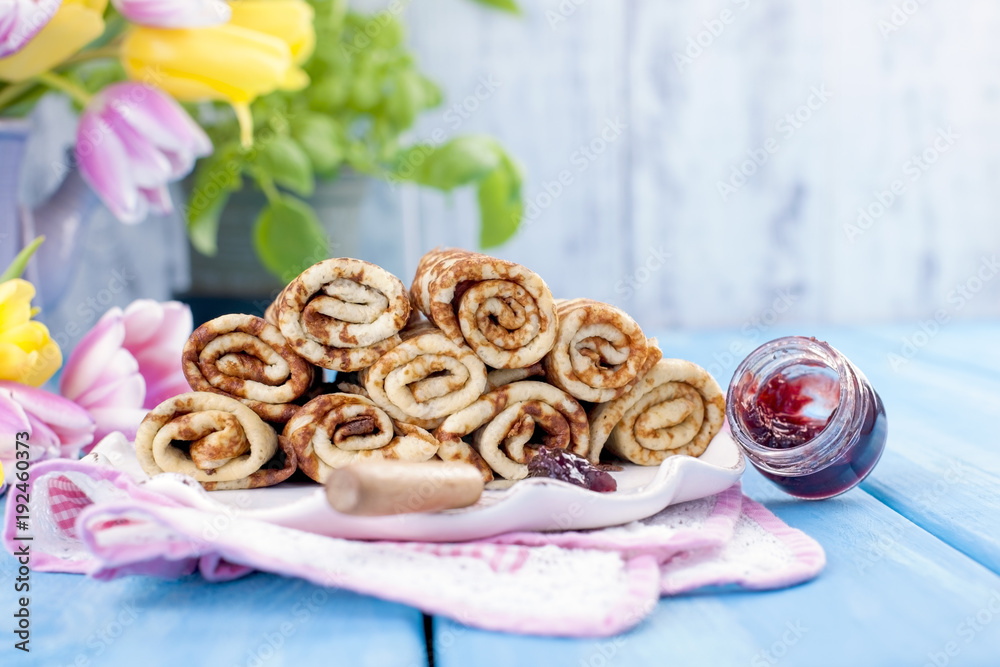 Homemade traditional pancakes with jam for spring carnival. Russian breakfast. Bright flowers of tulips. Blue background. Free space for text or a postcard. Homemade traditional pancakes with jam for spring carnival. Russian breakfast. Bright flowers of tulips. Blue background. Free space for text or a postcard.