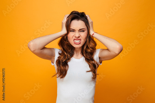 Displeased serious brunette woman in t-shirt holding her head