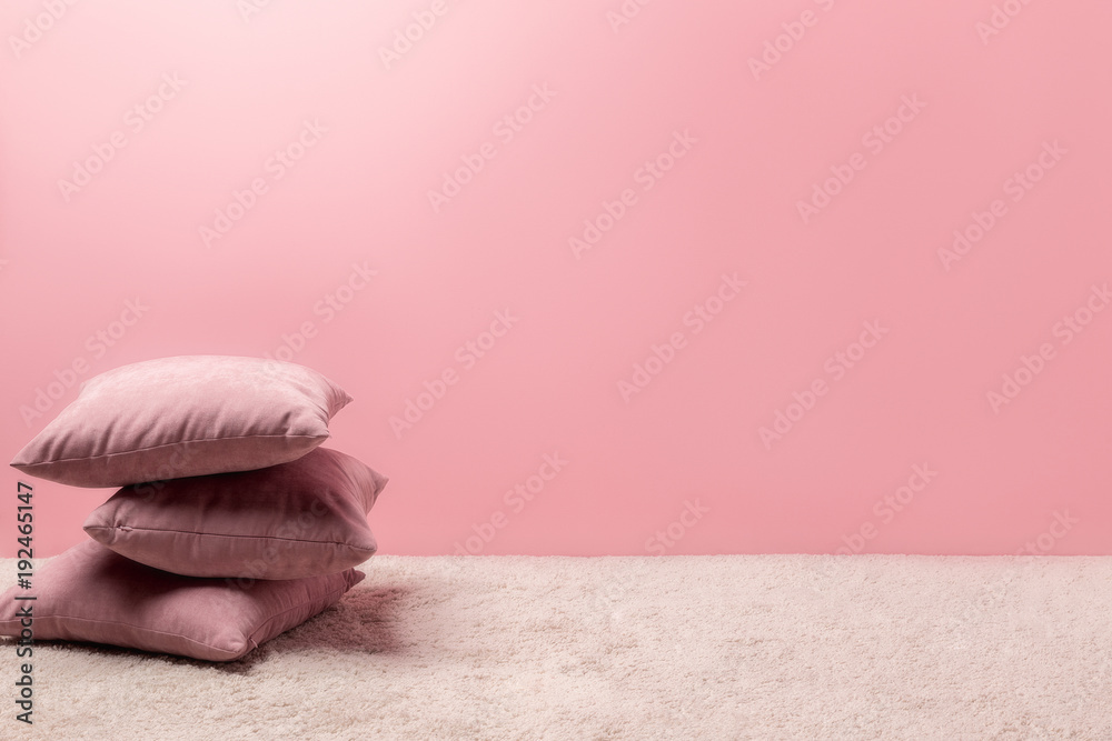 stack of pillows on carpet in front of pink wall - obrazy, fototapety, plakaty 