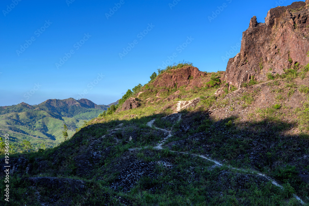 Dirt road in shadow of rock mountain with blue sky Dirt road in shadow of rock mountain with blue sky