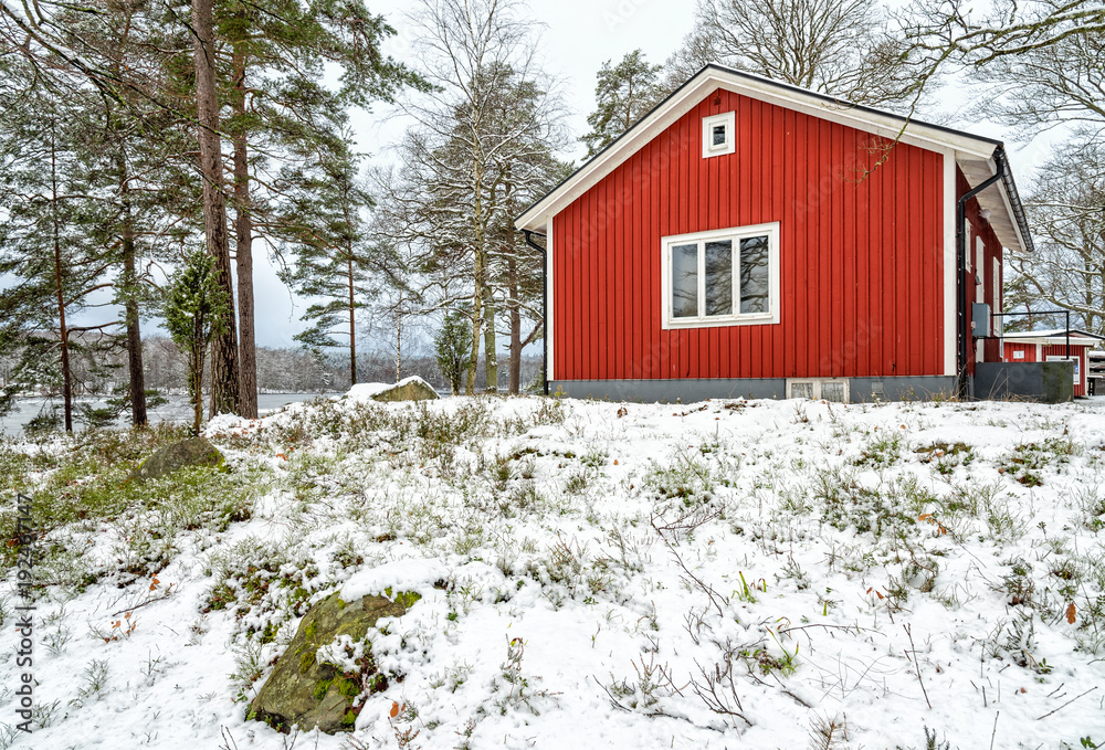 Typical Swedish red house in winter forest