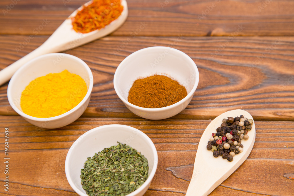 Plastic spoons and cups with dry spices and fresh herbs on a wooden rough boards background, top view, close up Plastic spoons and cups with dry spices and fresh herbs on a wooden rough boards background, top view, close up