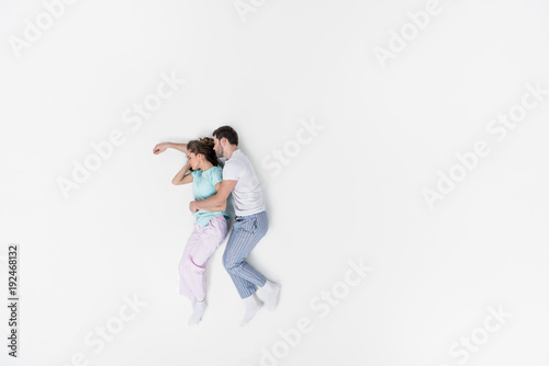 top view of couple in pajamas embracing and sleeping together isolated on white