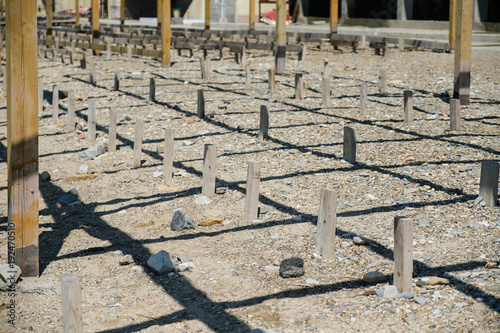 Close-up view of wood poles or sticks in pebble beach. Side view.