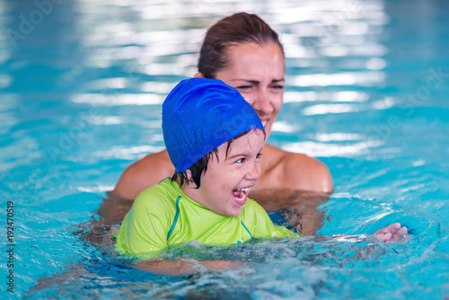 Little boy on swimming class with mother