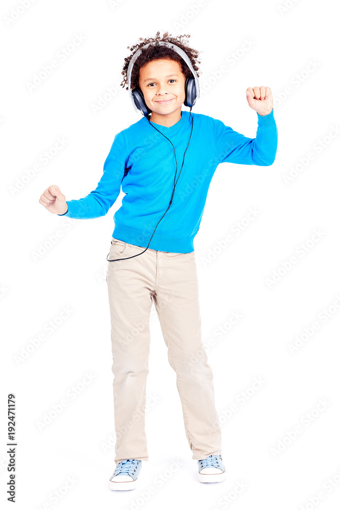 Portrait of cute curly-haired Latin American boy listening to music through earphones and dancing Portrait of cute curly-haired Latin American boy listening to music through earphones and dancing