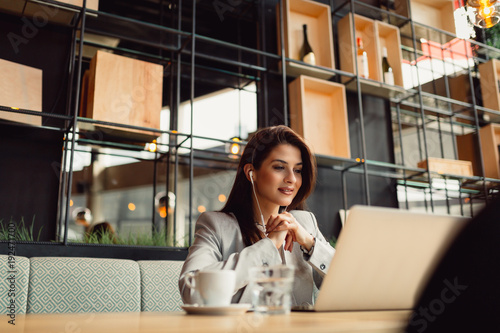 Portrait of young businesswoman using laptop in cafeteria.
