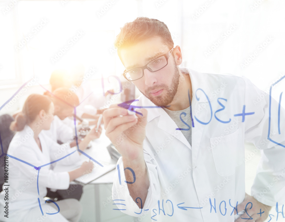 from behind the glass.scientist writes a marker on a glass Board from behind the glass.scientist writes a marker on a glass Board