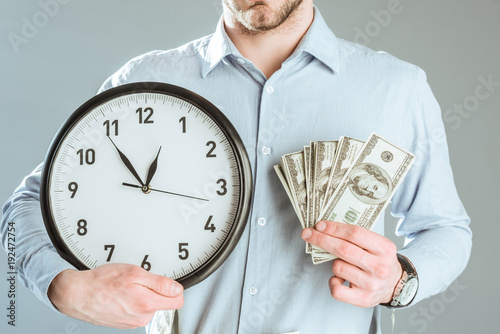 Bild auf Leinwand Close-up view of businessman showing money and clock isolated on grey