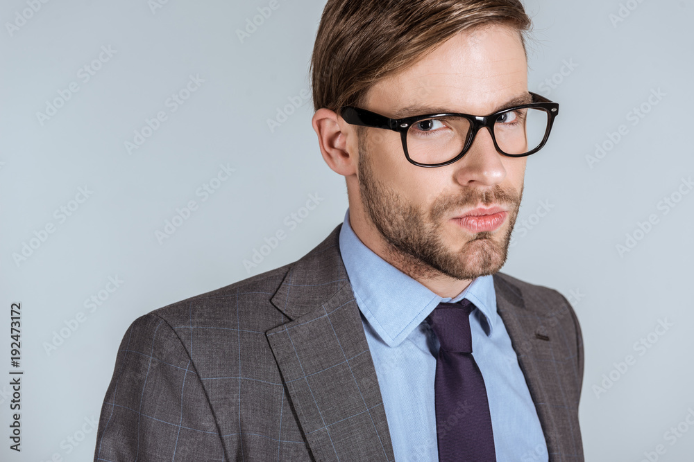 Young thoughtful businessman looking at camera isolated on grey Young thoughtful businessman looking at camera isolated on grey