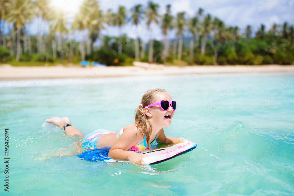 Kids surf on tropical beach. Vacation with child.