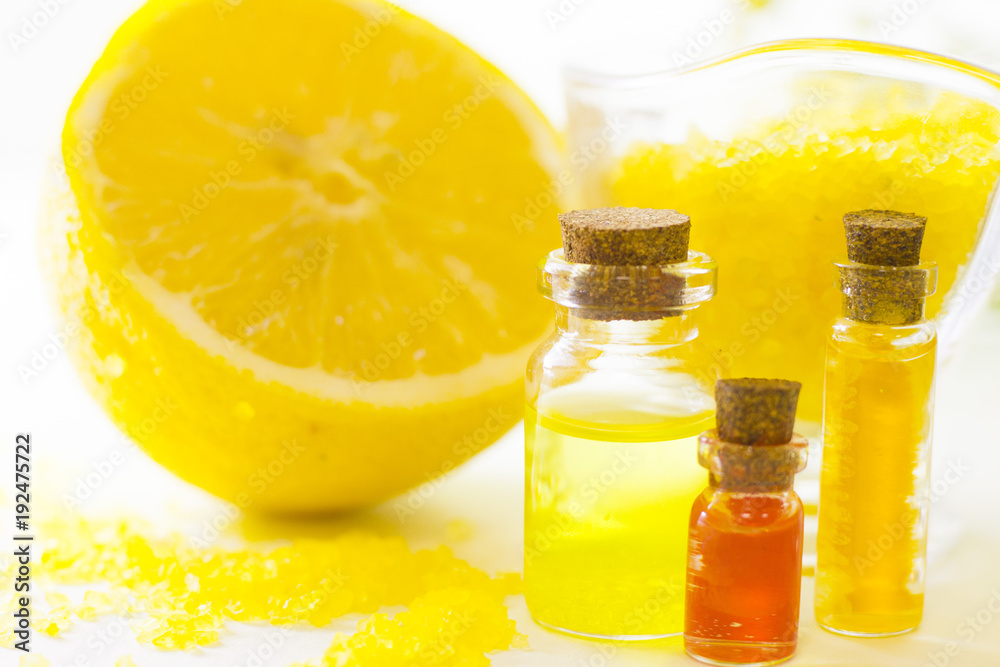 Fruit aromatherapy concept with essential oil in glass bottles, a bowl of bath sea salt, lemon, white background, close up Fruit aromatherapy concept with essential oil in glass bottles, a bowl of bath sea salt, lemon, white background, close up