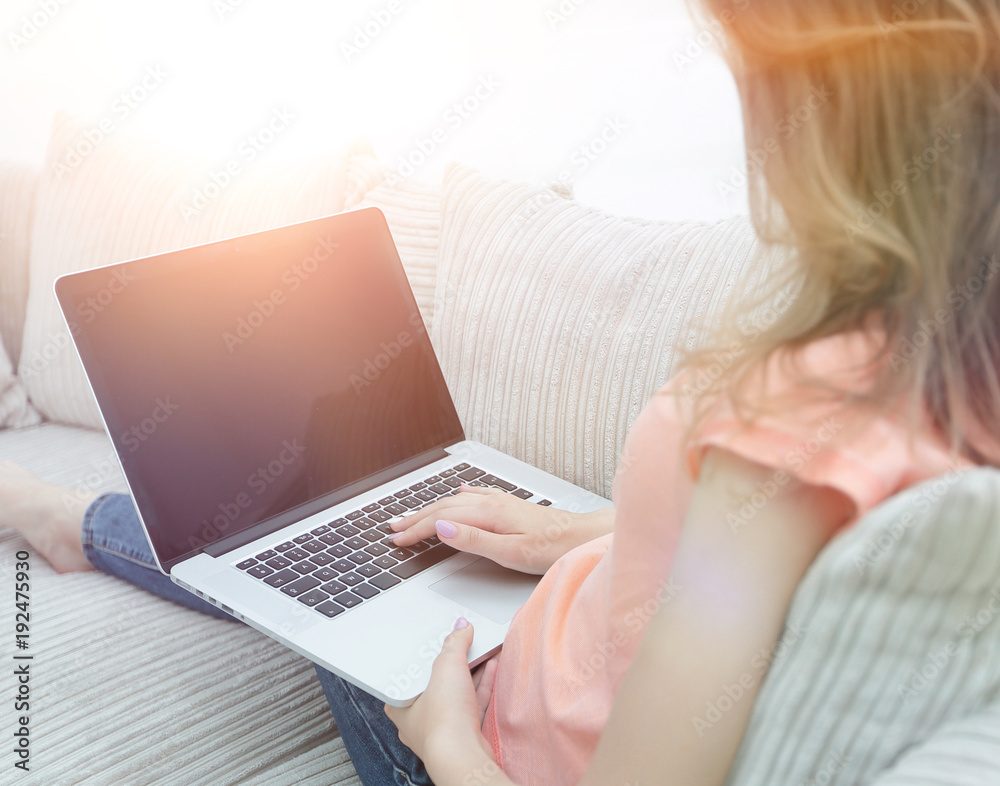 Fototapeta premium young woman working with laptop sitting on sofa