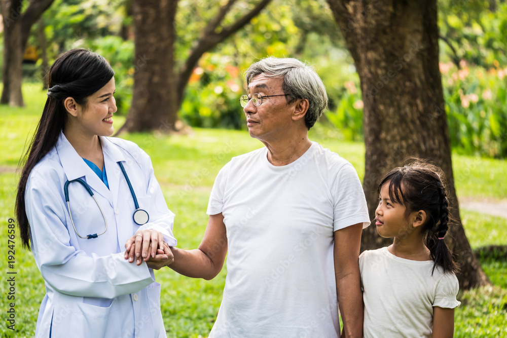 Young female doctor talking to senior patient with granddaughter in hospital garden Young female doctor talking to senior patient with granddaughter in hospital garden