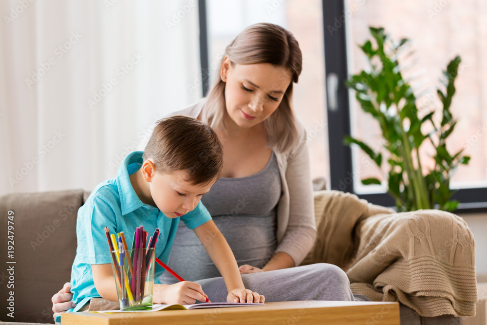 pregnant mother and son with workbook at home pregnant mother and son with workbook at home