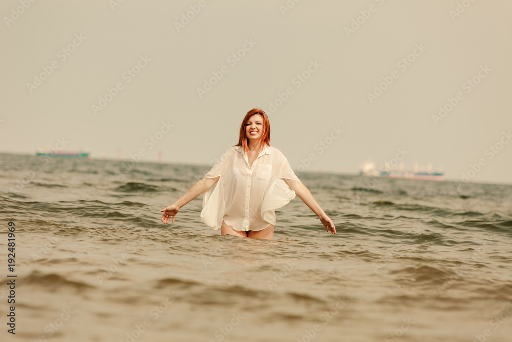 Redhead woman playing in water during summertime Redhead woman playing in water during summertime