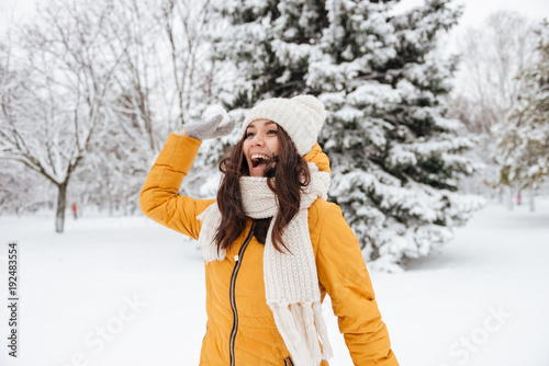 Playful young woman playing snowballs in park in winter