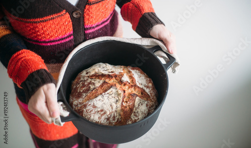 Woman with freshly baked homemade bread in a cast iron pot