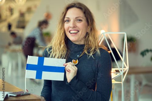 Scandinavian woman holds the flag of Finland in the background on the premises of the cafe.