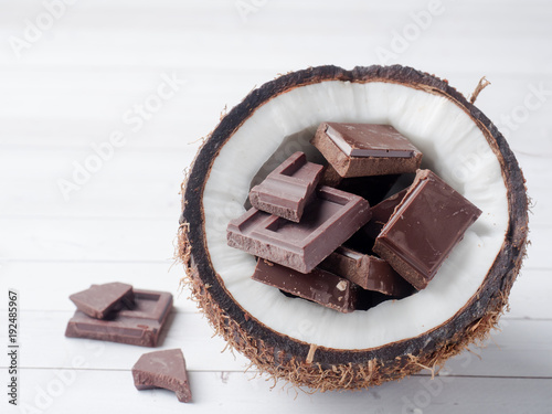 Fresh organic coconut broken into two parts with chocolate on a rustic wooden background