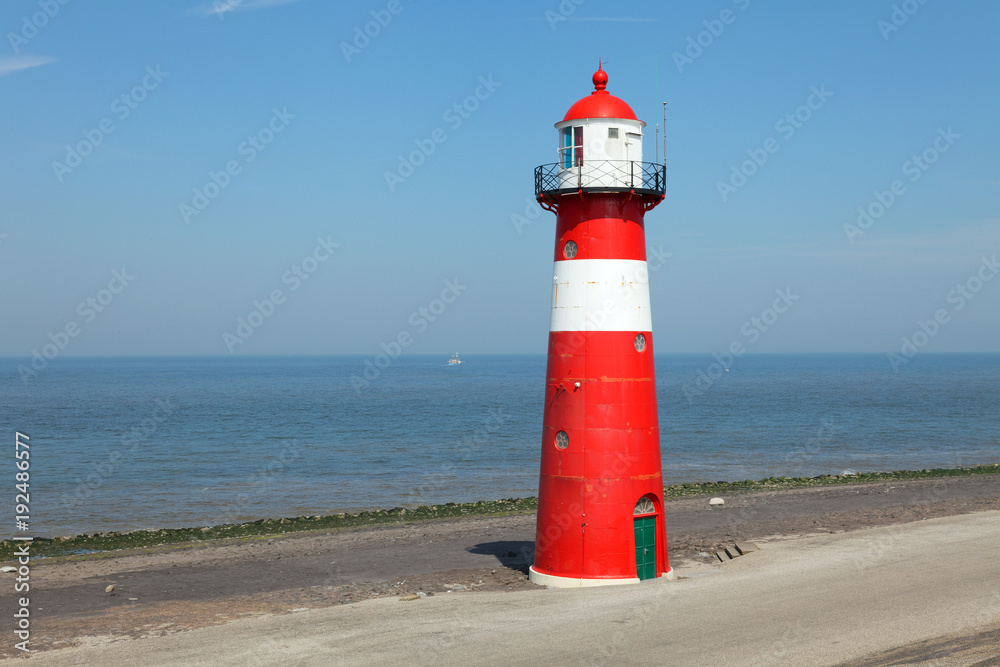 Red lighthouse on a dike seawall by the blue sea Red lighthouse on a dike seawall by the blue sea