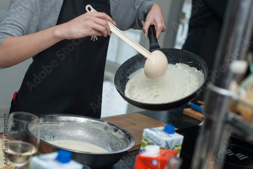 Process of Making Traditional Thin Pancakes in a Frying Pan. Woman Pours the Batter into a Thin Pancake Pan. Soft focus. Food Recipe.