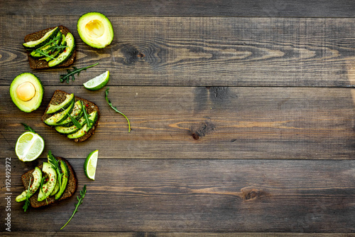 Have a bite with healthy snacks. Avocado toast on dark wooden background top view copy space