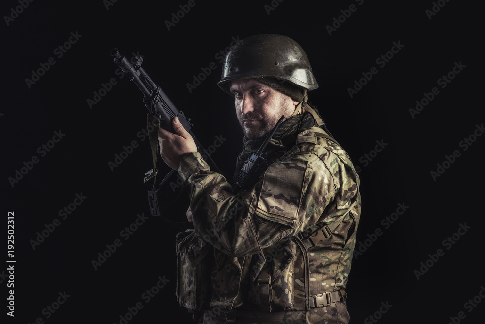 The volunteer on black background with guns and a walkie-talkie