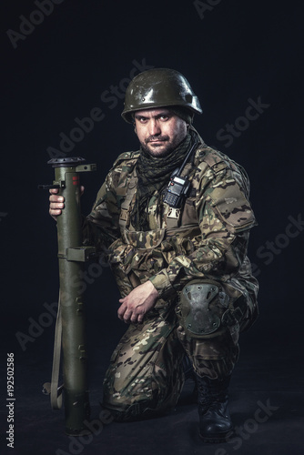 The volunteer on black background with guns and a walkie-talkie