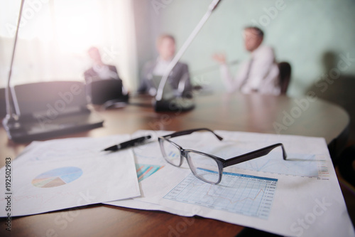 financial chart near dollars seen by unfocused glasses ( colleagues meeting to discuss their future financial plans only silhouettes being viewed ) 