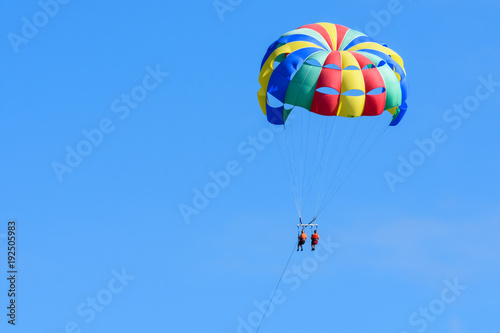 Tourists enjoying island parasailing in a blue sky of Roatan, Honduras.