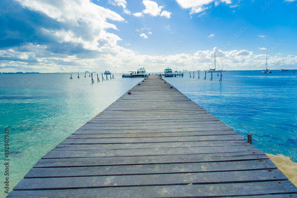 Outdoor view of a wooden dock into blue tropical sea in Isla Mujeres, Yucatan Mexico