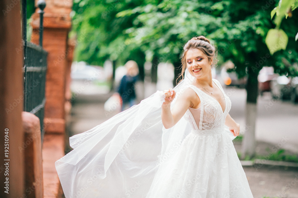 Gorgeous bride looks up in the sky standing on summer street. Beautiful woman on her wedding day. Gorgeous bride looks up in the sky standing on summer street. Beautiful woman on her wedding day.