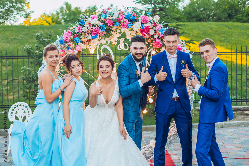 elegant stylish happy guests and bride and groom having funny photos on the background of arch, photo booth. Wedding moments with bridesmaids and groomsmen.