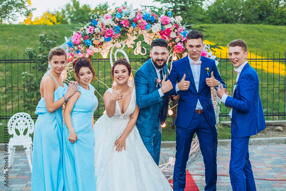 elegant stylish happy guests and bride and groom having funny photos on the background of arch, photo booth. Wedding moments with bridesmaids and groomsmen.
