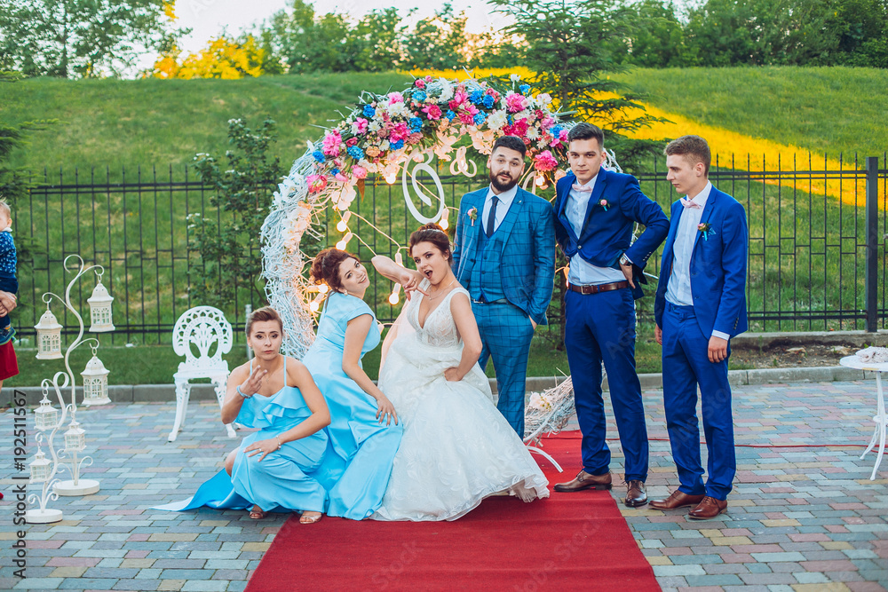 elegant stylish happy guests and bride and groom having funny photos on the background of arch, photo booth. Wedding moments with bridesmaids and groomsmen.
