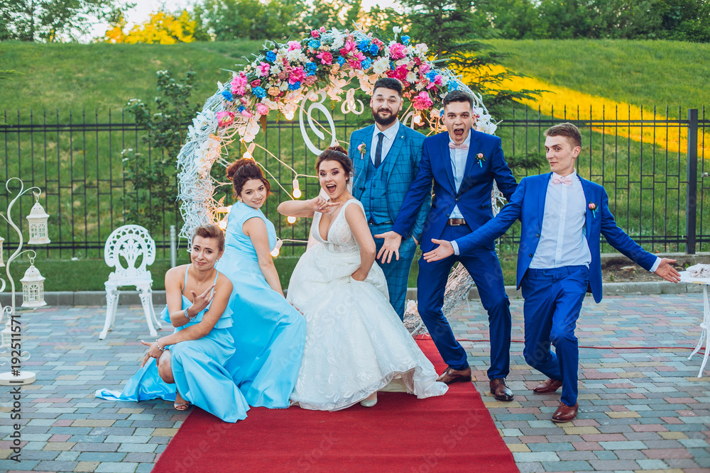 elegant stylish happy guests and bride and groom having funny photos on the background of arch, photo booth. Wedding moments with bridesmaids and groomsmen.
