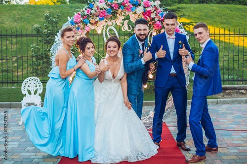 Obraz na płótnie elegant stylish happy guests and bride and groom having funny photos on the background of arch, photo booth. Wedding moments with bridesmaids and groomsmen. w salonie