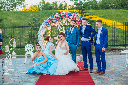 elegant stylish happy guests and bride and groom having funny photos on the background of arch, photo booth. Wedding moments with bridesmaids and groomsmen.