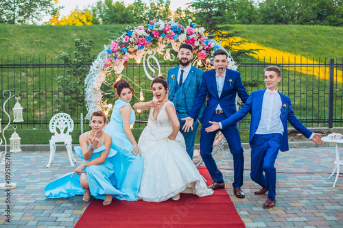 elegant stylish happy guests and bride and groom having funny photos on the background of arch, photo booth. Wedding moments with bridesmaids and groomsmen.